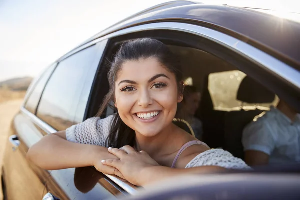 微笑的妇女纵向看着车窗外享受公路旅行 — 图库照片