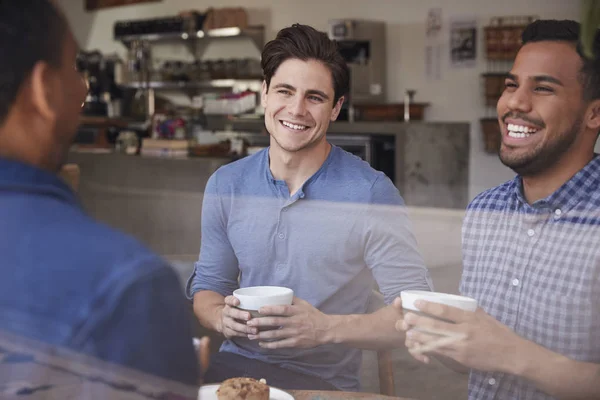 コーヒー ショップでコーヒーを飲みながら笑っている 人の男性友人 — ストック写真
