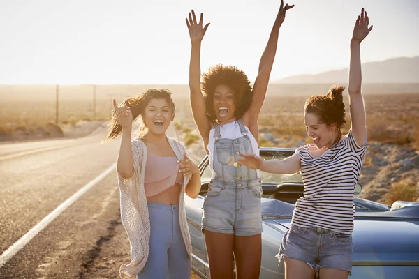 Female Friends Enjoying Road Trip Standing Next Classic Car Desert — Stock Photo, Image