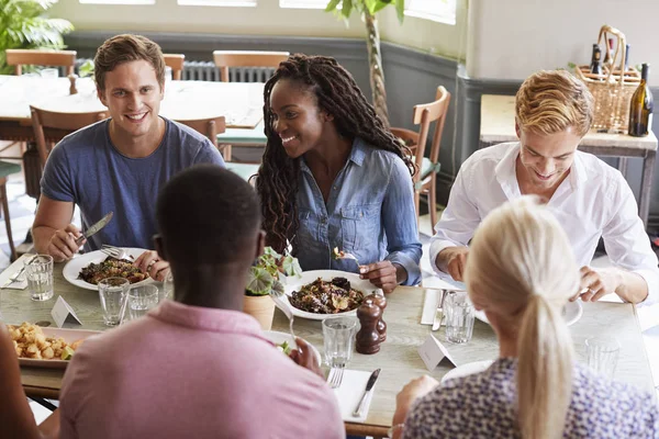 一群朋友坐在餐桌上一起享用美食 — 图库照片