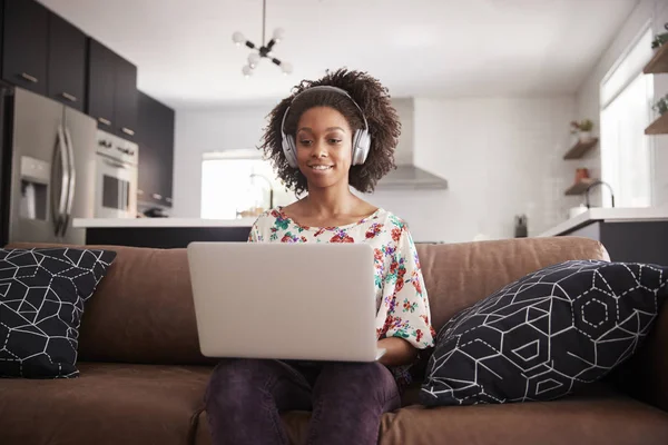 Mujer Con Auriculares Inalámbricos Sentada Sofá Casa Usando Ordenador Portátil —  Fotos de Stock