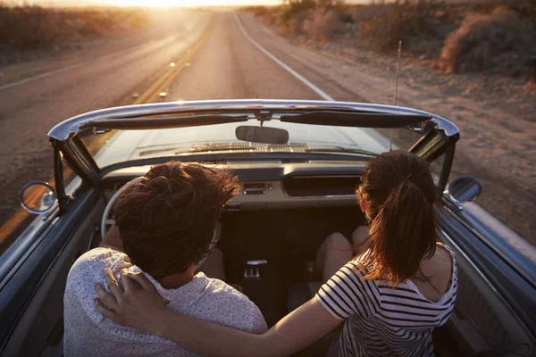 夕日に向かって古典的なコンバーチブルを運転道路旅行にカップルの後姿 — ストック写真