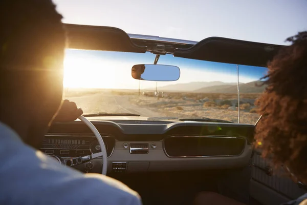 夫妇在公路旅行的后方视图驾驶经典敞篷车朝向日落 — 图库照片
