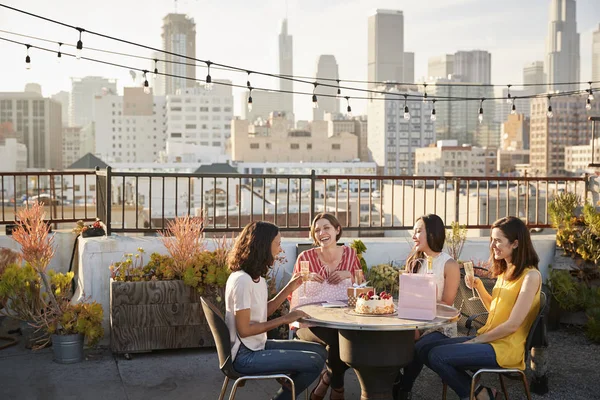 女性朋友庆祝生日在屋顶露台与城市天际线背景 — 图库照片