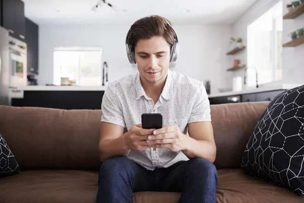 Mannen Bär Trådlösa Hörlurar Sitter Soffan Hemma Streaming Från Mobiltelefon — Stockfoto