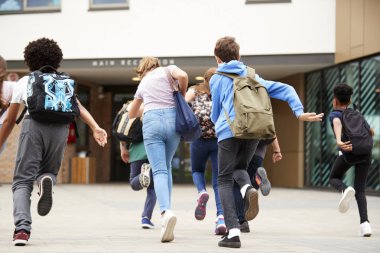 Group Of High School Students Running Into School Building At Beginning Of Class clipart