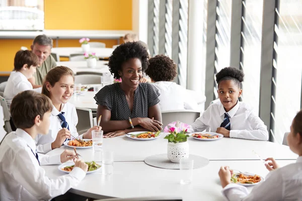 女教师与一群高中生在餐桌上 在自助餐厅吃午餐 — 图库照片
