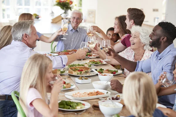 一群多代家人和朋友围坐在桌旁 边吃饮料一起吃食物 — 图库照片
