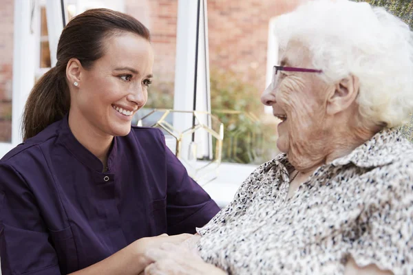 坐在椅子上与退休家庭中的照顾者交谈的女性住院医师 — 图库照片