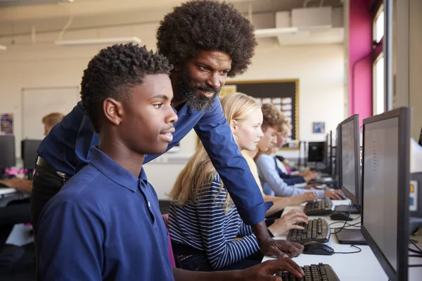 先生コンピューターのクラスでの作業 代男性高校生を支援 — ストック写真