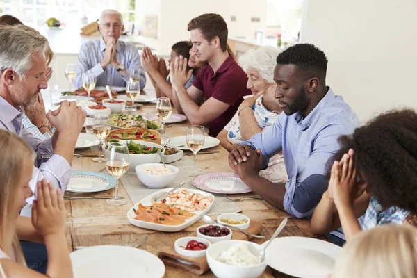Mehrgenerationenfamilie Und Freunde Beten Tisch Mit Essen Und Getränken — Stockfoto