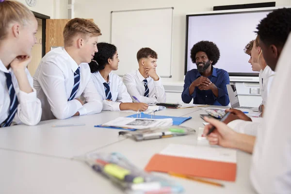Männlicher Gymnasiallehrer Sitzt Mit Teenagern Tisch Die Einheitliche Unterrichtsstunden Tragen — Stockfoto