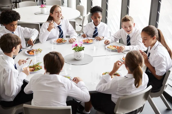 Grupo Estudantes Ensino Médio Vestindo Uniforme Sentado Torno Mesa Almoçando — Fotografia de Stock