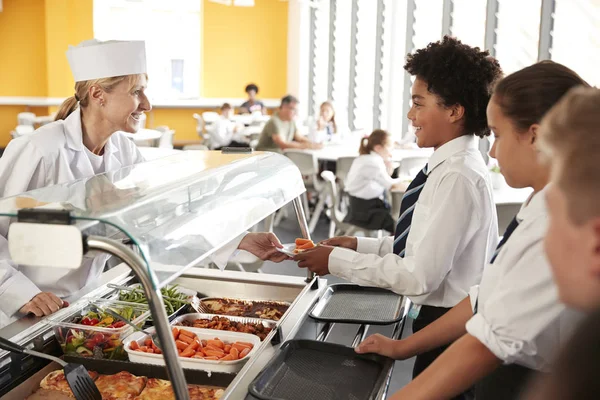 食堂で食べ物を提供されている制服を着て高校生 — ストック写真