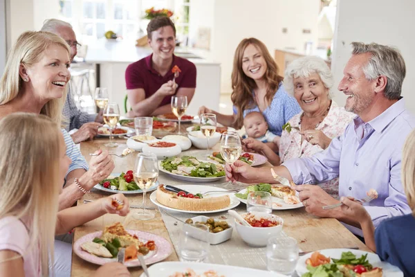 一群多代家人和朋友围坐在桌旁 边吃饮料一起吃食物 — 图库照片