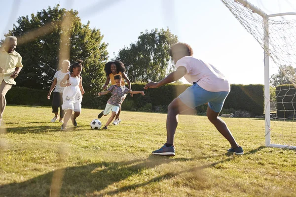 Multi-generation african american family playing football in a garden