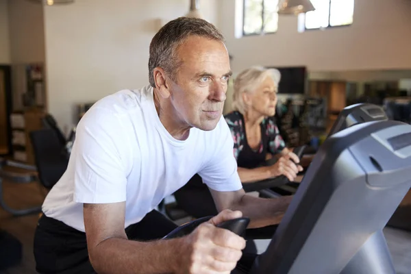 Aktives Senioren Paar Trainiert Fitnessstudio Auf Radsportgeräten — Stockfoto