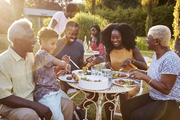 庭のテーブルで食べるアフリカ系アメリカ人の多世代家族 — ストック写真