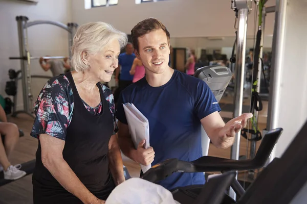 Seniorin Die Fahrradmaschine Trainiert Wird Von Männlichem Personal Trainer Fitnessstudio — Stockfoto