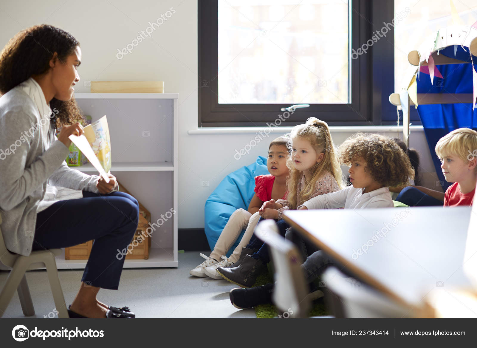 Side View Female Kindergarten Teacher Sitting Chair Showing Book
