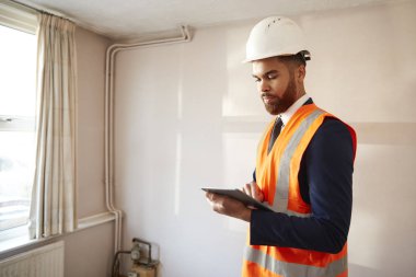 Surveyor In Hard Hat And High Visibility Jacket With Digital Tablet Carrying Out House Inspection clipart
