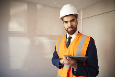 Portrait Of Surveyor In Hard Hat And High Visibility Jacket With Digital Tablet Carrying Out House Inspection clipart
