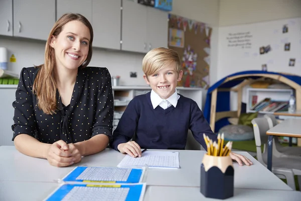 Jonge Vrouwelijke Basisschoolleraar School Jongen Zittend Aan Een Tafel Kijkend — Stockfoto