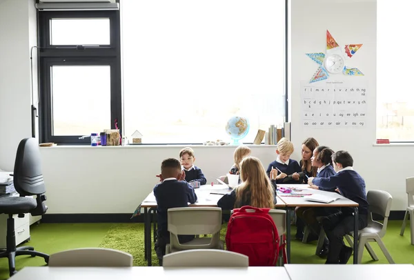 Group Primary School Kids Sitting Table Classroom Teacher Kneeling Help — Stock Photo, Image