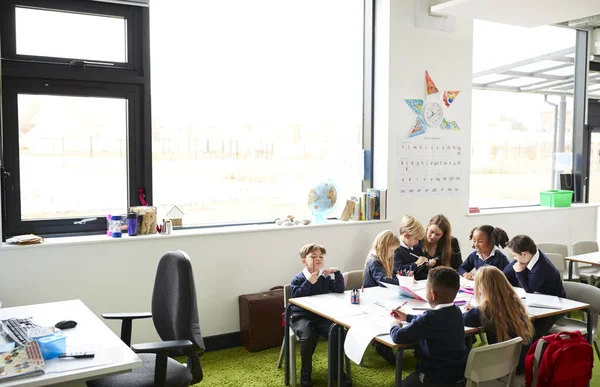 Női Tanár Elemi Iskolában Gyerekekkel Asztalnál Osztályban — Stock Fotó
