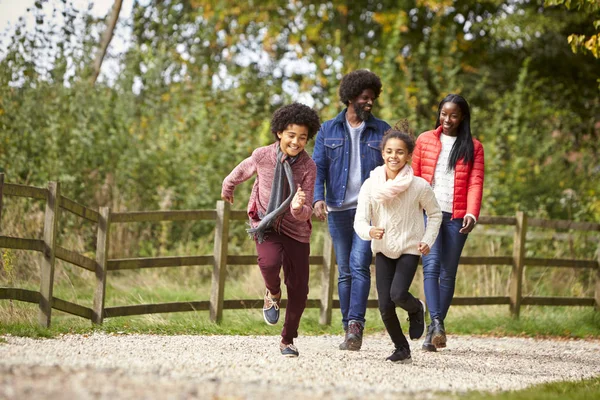 Mixed race children running ahead of their parents on a path during family walk in the countryside