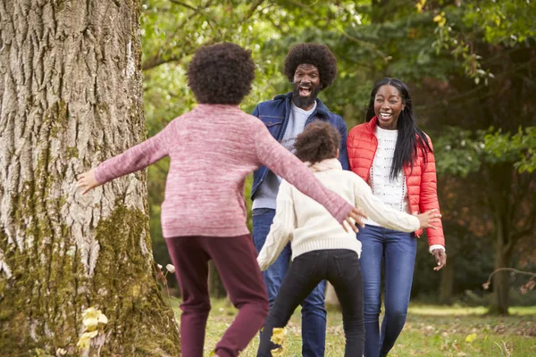 Dwoje Dzieci Wyskakując Zza Drzewa Zaskakiwać Rodziców Podczas Spaceru Parku — Zdjęcie stockowe