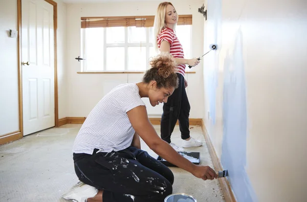 两个女人在新家装饰房间和画墙 — 图库照片
