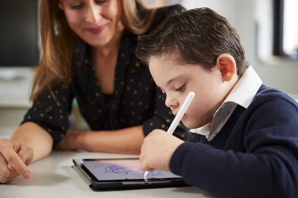 초등학교 교실에서 태블릿 컴퓨터를 사용하여 증후군 남학생과 책상에 교사의 — 스톡 사진