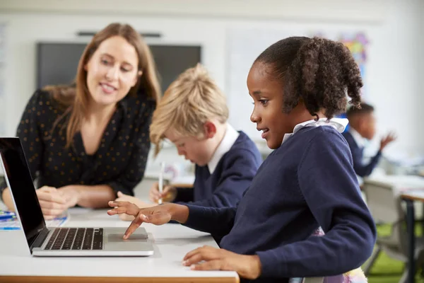 초등학교 수업에서 노트북 컴퓨터를 사용하는 소년과 소녀를 책상에 앉아있는 여학생 — 스톡 사진