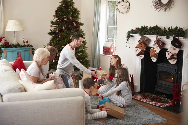 在圣诞节的休息室里 三代家庭穿着睡衣 打开礼物 — 图库照片