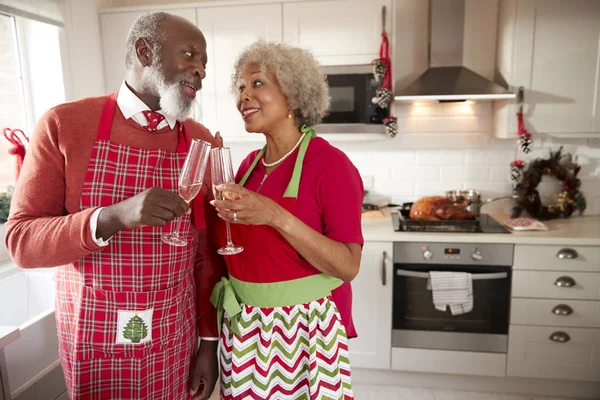 Senior black couple wearing aprons take a break from preparing Christmas dinner to make a toast