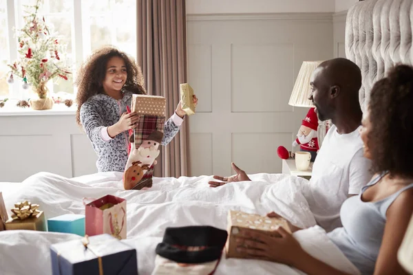 圣诞节早上 年轻的混血女孩给父母送礼物 父母坐在床上 — 图库照片