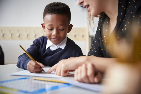 Grundschullehrerin Hilft Einem Kleinen Schuljungen Der Einem Klassenzimmer Tisch Sitzt — Stockfoto