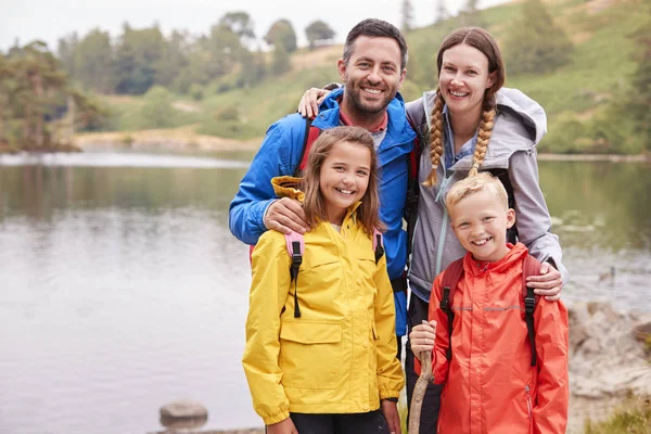 笑みを浮かべて 湖水地方 英国のカメラを探して田舎で湖の岸に立って若い家族います — ストック写真