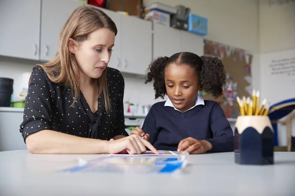 Young Female Primary School Teacher Working One One Schoolgirl Table — Stock Photo, Image