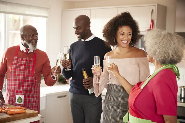 混血高三和年轻的成年家庭举起香槟酒眼镜庆祝 同时在厨房里一起准备圣诞晚餐 — 图库照片