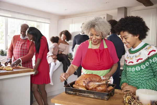 多世代家族はクリスマス ディナー 祖母と孫のフォア グラウンドでロースト七面鳥を準備する前にキッチンで集まった混血 — ストック写真