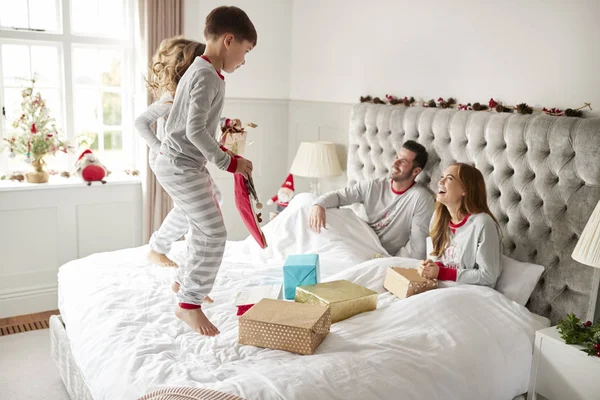 Возбужденные Дети Прыгают Кровати Родителей Дома Семейные Подарки Рождество — стоковое фото