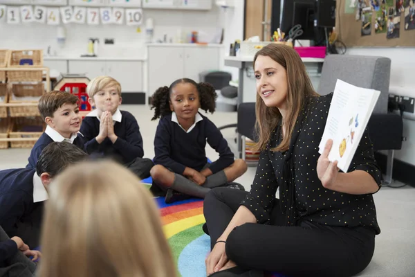 Niños Escuela Primaria Sentados Suelo Aula Con Maestro Sosteniendo Libro —  Fotos de Stock