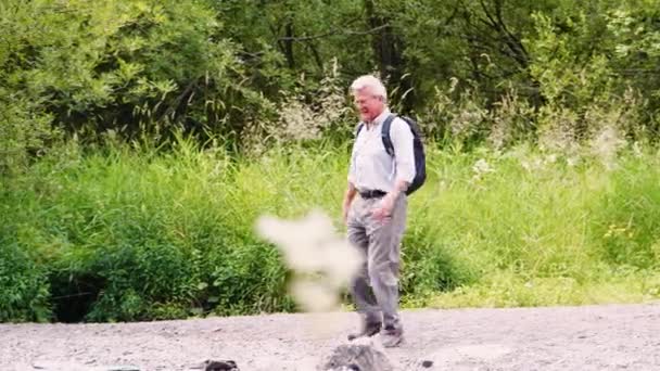 在屋湖区使用垫脚石的高级男性徒步者过河的全长侧视图 慢动作拍摄 — 图库视频影像