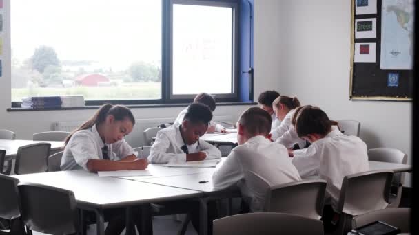 Grupo Estudiantes Secundaria Con Uniforme Sentado Los Escritorios Aula Escribiendo — Vídeo de stock