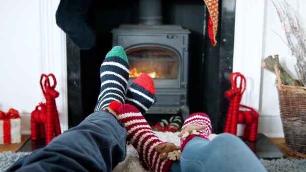 Videoaufnahme Von Paar Weihnachtssocken Die Sich Vor Dem Kamin Gemütlich — Stockvideo