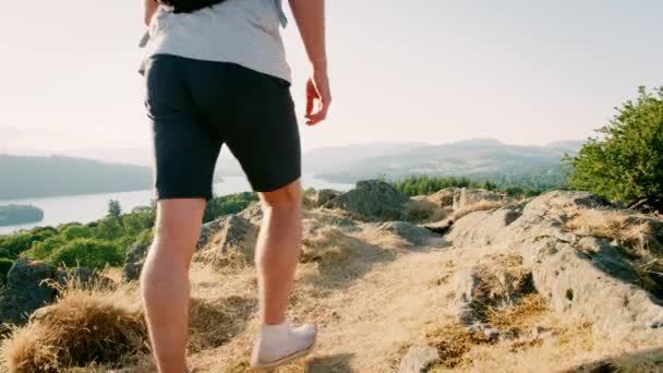 美しい風景 スローモーションで撮影を見てイギリス湖水地方でのハイキングに丘の上に立っているバックパックを身に着けている若いカップルの背面図 — ストック動画