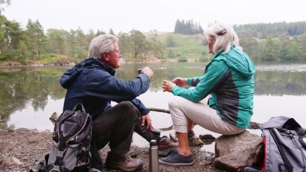 Casal Sênior Sentado Rochas Perto Lago Rindo Conversando Durante Umas — Vídeo de Stock