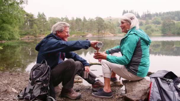 在英国湖区野营度假期间 坐在湖边喝咖啡的老年夫妇 — 图库视频影像